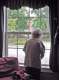 Elderly woman peering out window
